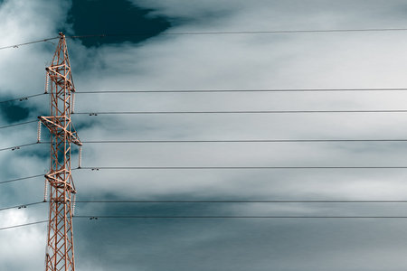 Rusty high-voltage towers with wires. The construction is made of metal corners and rivets.