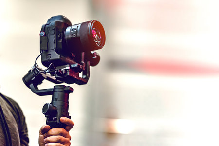 Video shooting with a camera with a tripod with a black stabilizer. The background is blurred.の写真素材