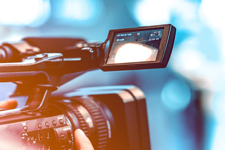 Video shooting with a camera with a tripod with a black stabilizer. The background is blurred.の写真素材