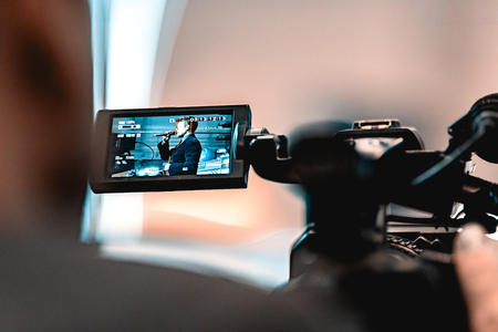 Video shooting with a camera with a tripod with a black stabilizer. The background is blurred.の写真素材