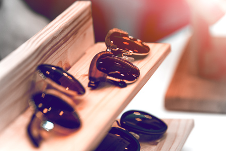 Sunglasses on the shelf put in a row. The frame is made of metal and wood. The background is blurred.の写真素材