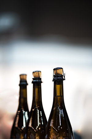 Several glass bottles of champagne with stoppers. Tube holding the wire. The background is blurred.の写真素材