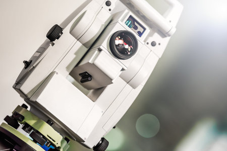 Electronic optical measuring device in white. Has the lens and viewfinder. The background is gray...