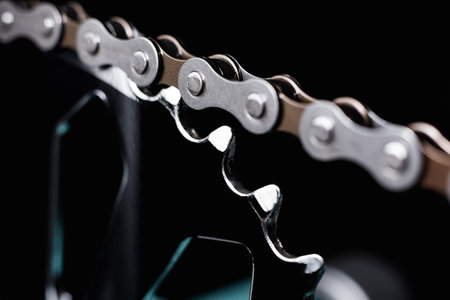 Dark metallic chain of a Bicycle filmed in close up. small details are visible. The background is...