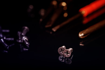 Black screws on a dark background. Screws scattered in a chaotic manner. Table glossy black.