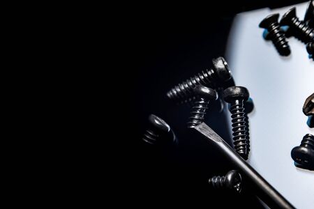Black screws on a dark background. Screws scattered in a chaotic manner. Table glossy black.の写真素材
