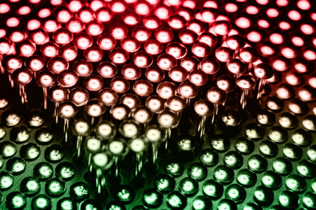 A lot of shiny little nails on a dark background arranged tightly together. Shallow depth of field.
