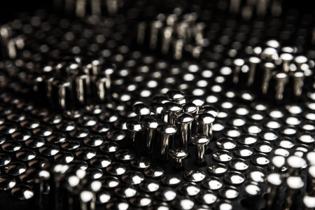 Lots of shiny little studs on a dark background arranged tightly together. Shallow depth of field.