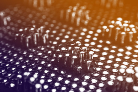 Lots of shiny little studs on a dark background arranged tightly together. Shallow depth of field.