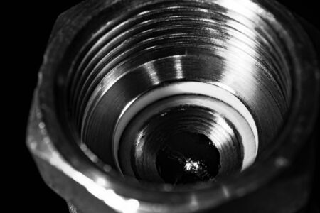 Brass plumbing product on a dark blurred background. In the foreground close-up visible carving.の写真素材