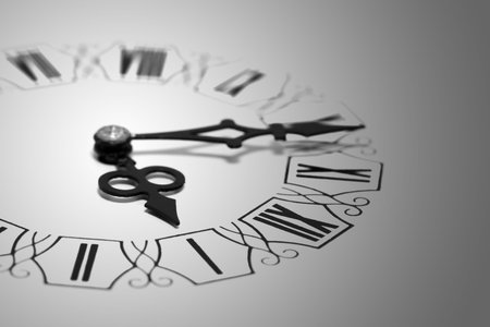White clock with Roman numerals and black hands. The numbers have recesses in the dial.