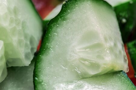 Cut fresh tomatoes and cucumbers of different shapes. Visible water droplets and the seeds of the fruit.の写真素材