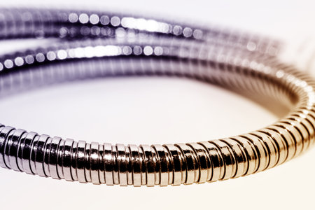 Metal flexible tube retainer for electrical appliances. Low depth of field. The background is light.