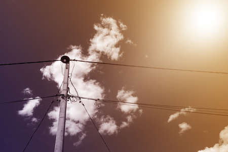 Concrete old electric pole with a lot of tangled wire against a clear sky.の写真素材