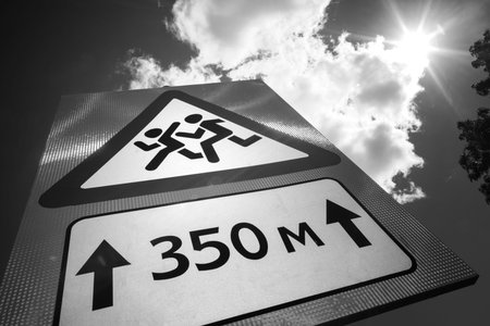 Road sign: Caution, children. The sign is photographed against a cloudy daytime sky.