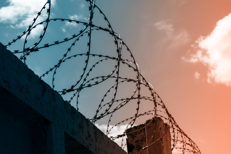 Round barbed wire against a clear sky. There is a slight cloud cover.
