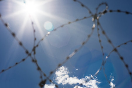 Round barbed wire against a clear sky. There is a slight cloud cover.