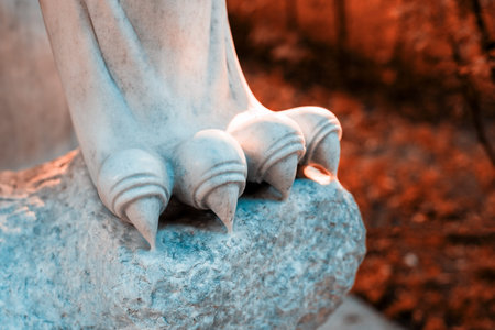Fragment of paws and claws of a lion statue made of white marble against the background of trees in the Park. Small details of the sculpture are visible.の写真素材