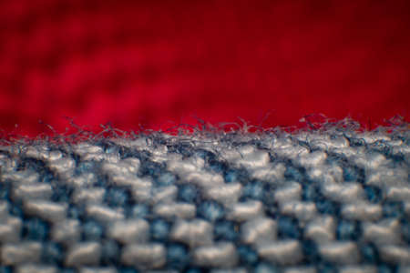 Synthetic fiber photos of denim There is a space between the fibers. Tidy weave, blue-white fibers, high magnification, super macro. The background is blurred red cloth.の写真素材