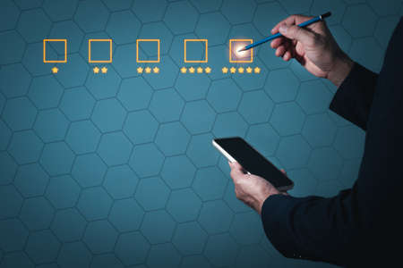 A man wearing a suit on his left hand holding a cell phone Right hand holding a pencil Make a poke at the square with five stars.の写真素材