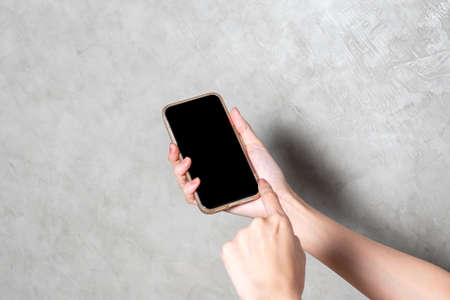 A woman's right hand holding a cell phone Left hand pointing at the screen Focus on the screenの写真素材