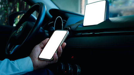 Left hand of a man holding smartphone,white screen, protruding at car stereo,concept is a connection...