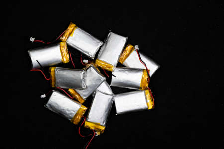 Used batteries, wrapped in silver and yellow, removed from toys, placed before being recycled and disposed of, on a black background.の写真素材