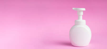 White bottle of shampoo or lotion isolated on pink background. Shadows blur on the floorの写真素材