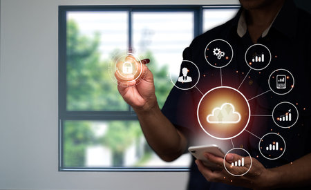 A man in a suit uses his left hand to hold the cloud computing symbol in his hand and the business...