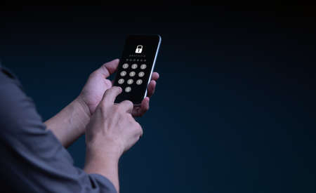 Businessman with a mobile phone is secure in his account. The concept is hacking a Phishing mobile phone with a password to access a smartphone, security threats online, and fraud.の写真素材