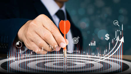 A red dart is being placed into the middle of a circular target in the right hand of a man in a suit. Concep's goal is to attain it.の写真素材