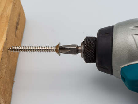 On the solid wood work bench, a carpenter uses an electric screwdriver.の写真素材