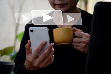 A lady is using her mobile phone to stream online, view videos on the internet, or attend a live...