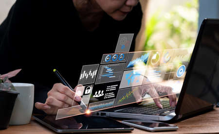 Concept of business analysis, solution, and planning A businesswoman and a finance analyst work on a computer tablet, studying sales data and an economic growth graph chart.の写真素材