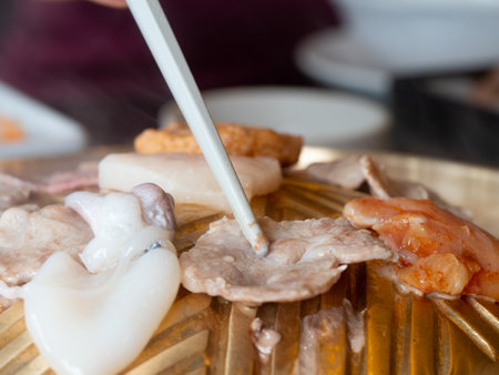 The pork is roasted on a barbeque using white chopsticks, where heat and smoke emanate from the dish.の写真素材