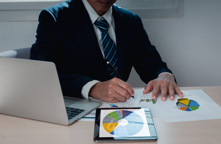 Businessman working at his desk with a laptop, digital tablet, and paperwork. That includes business...