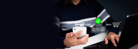 A man with a mobile phone and a laptop computer, making an online payment, banking, and buying using...