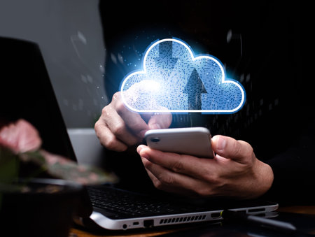 A man is using a laptop computer and a mobile phone while looking at a cloud computing diagram....