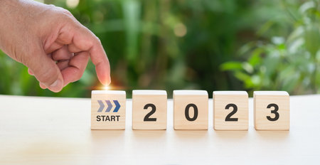 A businessman taps a word start virtual download bar with a loading progress meter on New Year's Eve, turning the year 2023  on woodblogの写真素材