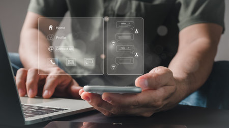 Businessman touching the virtual contact menu on his smartphone while using the phone, email, and...