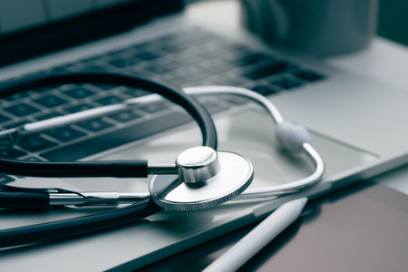 A stethoscope is placed on a laptop and a tablet computer. working on a computer at a clinic table in the background.の写真素材