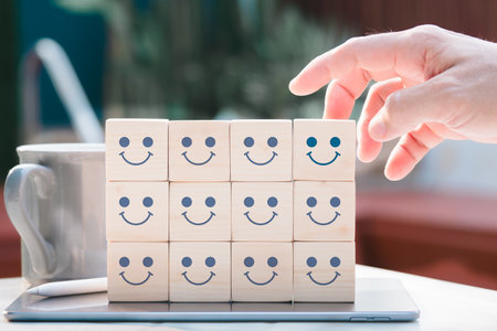 Mental health and emotional condition concept, choice of a positive mindset shown by a smiling face on the bright side of a wooden block cube.の写真素材