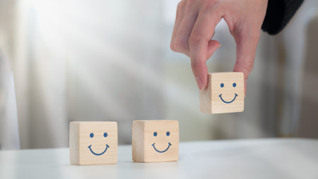 A happy smile is painted on the face of a wooden block cube to symbolize optimism. notion of...