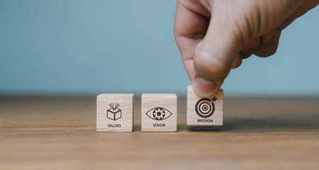 The company's mission, vision, values. purposeful business idea. A hand holds a wooden cube with...