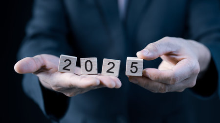 A businessman holding a wood cube with the year 2025 on it, suggesting the start of a new year and...
