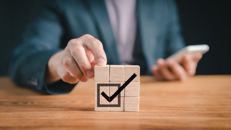 business compliance and regulations. Goal attainment, commercial success. completing the task. business ethics. Do the proper thing. both ISO, quality. placing a wooden cube with icon for a checkmark.の写真素材