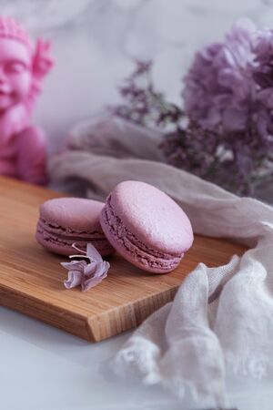 Violet macarons with flowers and pink Buda on white backgroundの写真素材