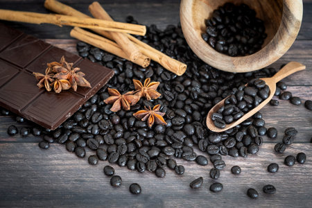 View of coffee beans, star anise, cinnamon stick, chocolate, coffee macaroons, mortar and wooden...