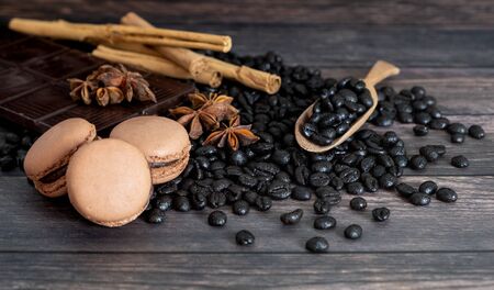 Coffee beans, macarons, star anise, dark chocolate, cinnamon stick, on wooden background.の写真素材