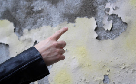 A man's hand in a black leather jacket points his finger at the wallの写真素材